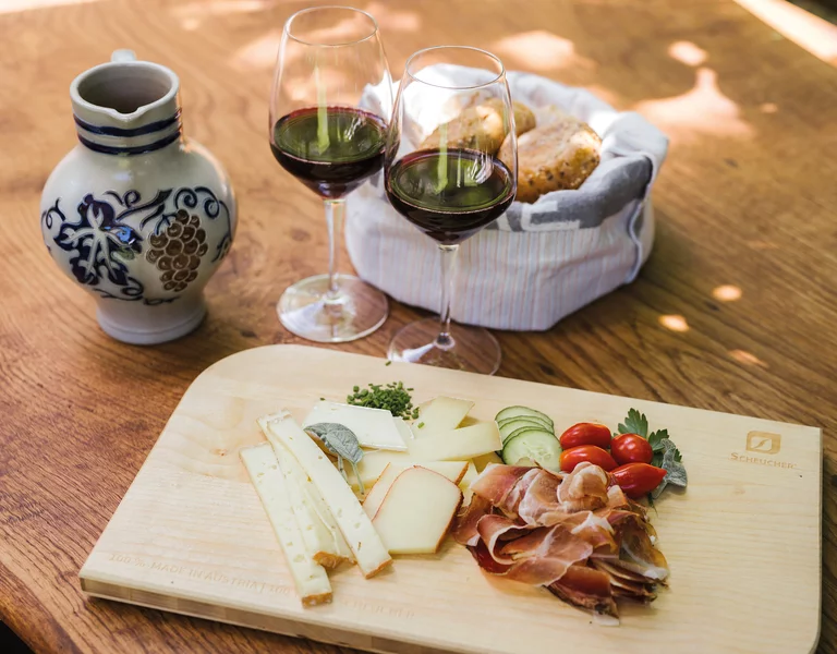 Holztisch mit Südtiroler Marende, Speck, Käse, Schüttelbrot und Rotwein.